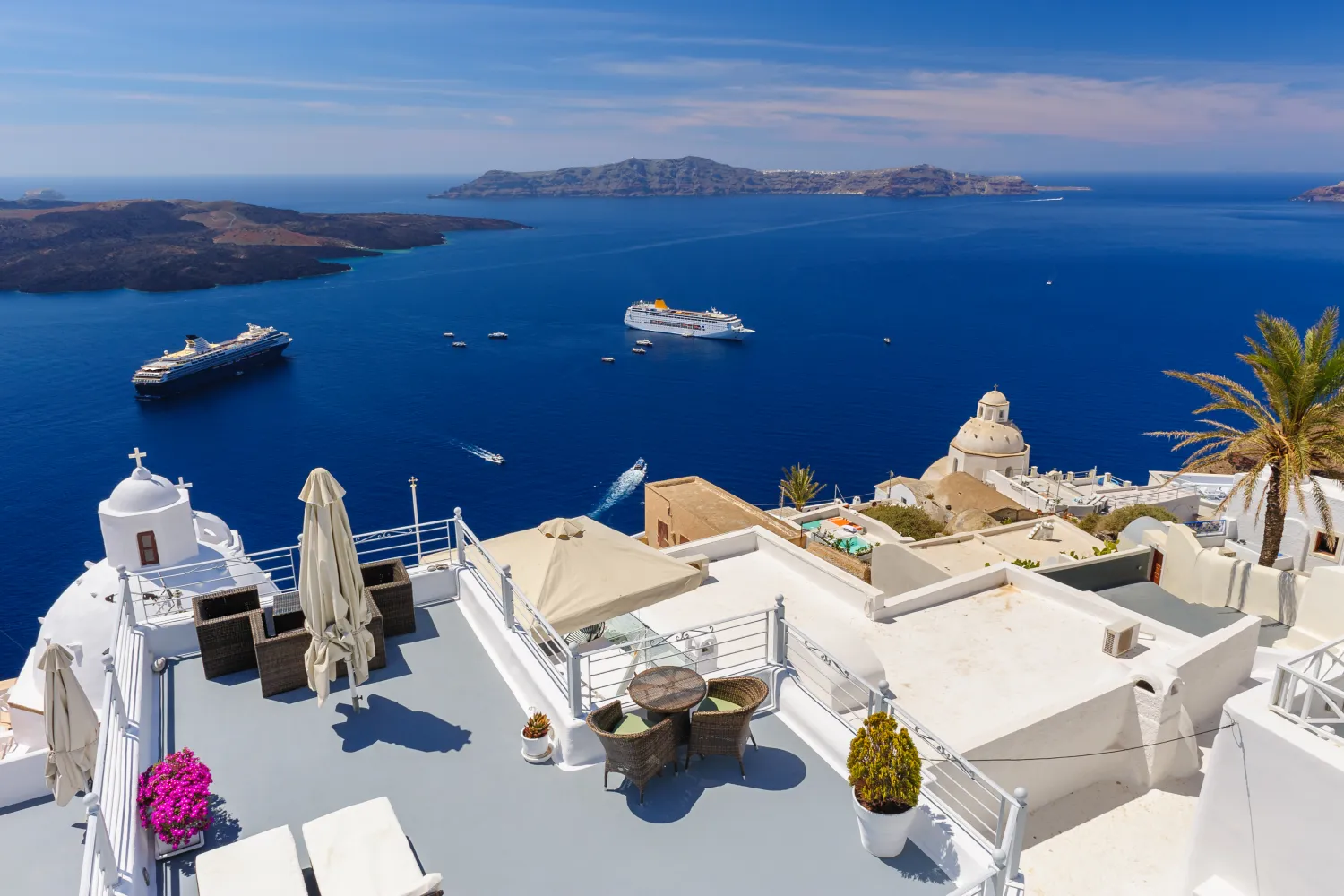 Blick auf die Caldera und Kreuzfahrtschiffe von der Terrasse eines Hotels